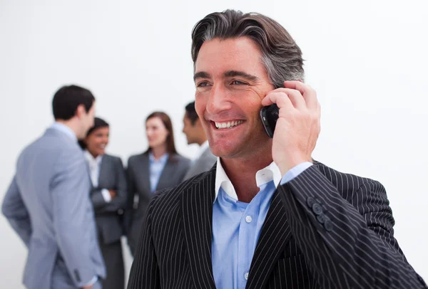 Aantrekkelijke manager op telefoon met zijn ploeg in de achtergrond — Stockfoto