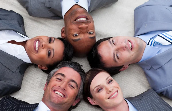 Multietniska verksamhet team liggande på golvet med huvuden ihop — Stockfoto