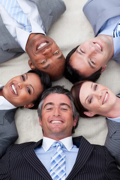Smiling business team sdraiato sul pavimento con la testa insieme — Foto Stock