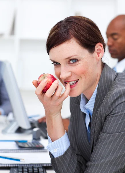 Empresária comendo uma fruta no trabalho — Fotografia de Stock
