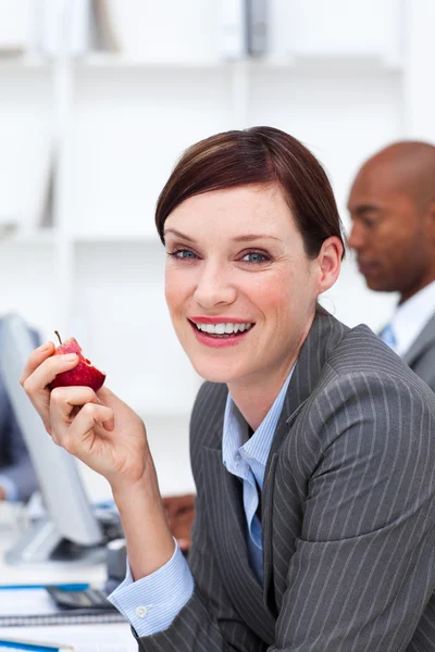 Портрет улыбающейся деловой женщины, поедающей яблоко — стоковое фото