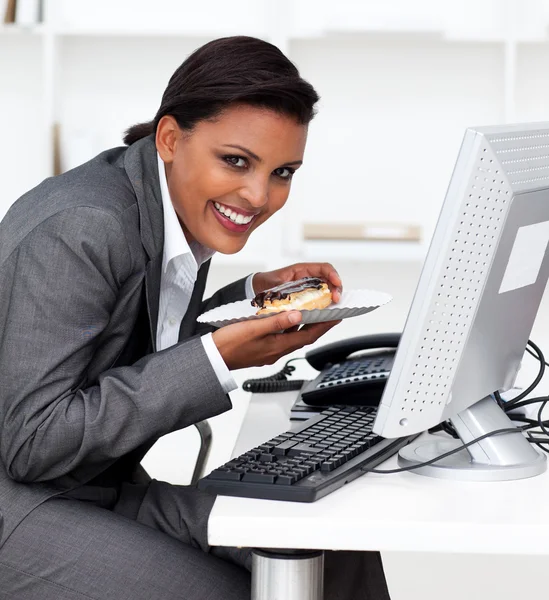 Empresária sorridente comendo uma pastelaria — Fotografia de Stock