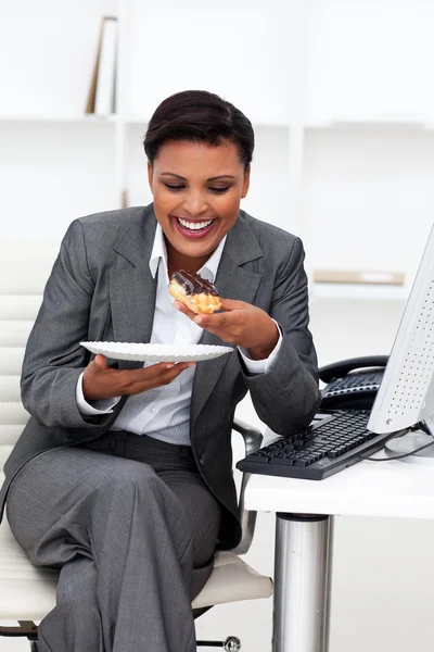 Glückliche Geschäftsfrau beim Essen im Büro — Stockfoto