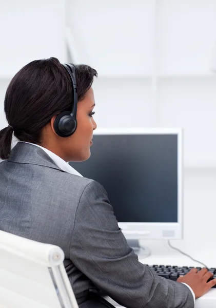 Ernstige zakenvrouw werkt op een computer met hoofdtelefoon op — Stockfoto