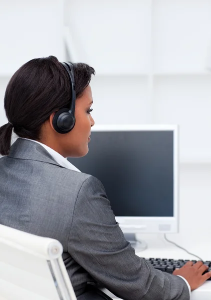 Femme d'affaires sérieuse travaillant à un ordinateur avec casque sur — Photo