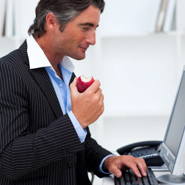 Närbild av en glad affärsman äta ett rött äpple — Stockfoto