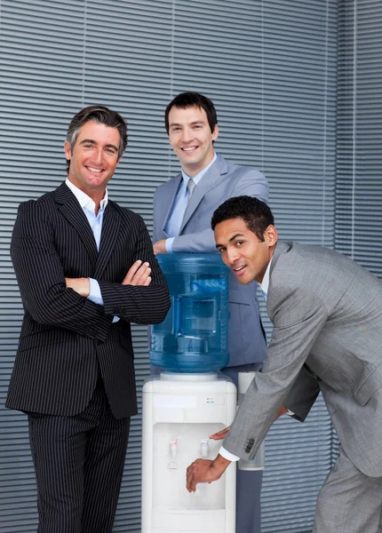 Portrait of a business team filling cup from water cooler — Stock Photo, Image