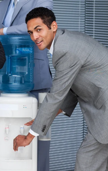 Привлекательный бизнесмен наполняет чашку из кулера для воды — стоковое фото