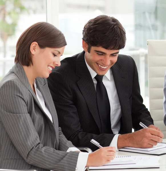 Two smiling colleagues studying sales report with their team — Stock Photo, Image
