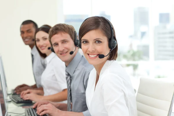 Happy co-workers with headsets on working in call center — Stock Photo, Image