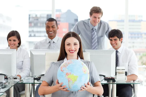 Brunett affärskvinna och hennes team visar en terrestrial globe — Stockfoto