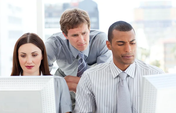 Empresarios serios trabajando en computadoras con su gerente — Foto de Stock