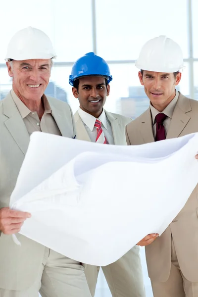 Smiling architects with hardhat looking at blueprints — Stock Photo, Image