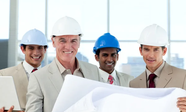 Smiling group of architect examining blueprints — Stock Photo, Image
