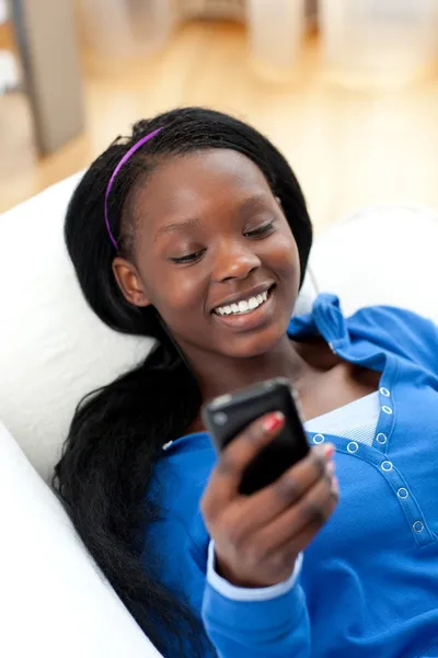 Glad kvinna skicka en text liggande på en soffa Stockfoto