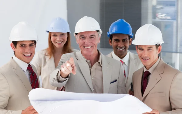 A group of smiling architects studying blueprints Stock Photo