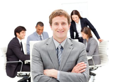 Assertive male executive with folded arms sitting in front of hi clipart
