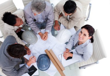 High angle of multi-ethnic architects studying blueprints clipart