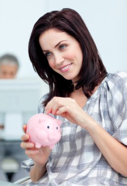 Delighted businesswoman saving money in a piggy-bank clipart