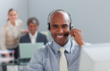 Afro-american businessman with headset on working at a computer clipart