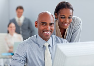 Portrait of two ethnic colleagues working at a computer clipart