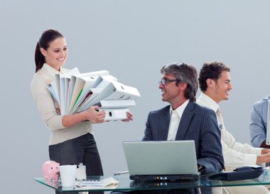 Pretty businesswoman carrying a stack of folders with her collea clipart