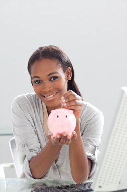 Confident ethnic businesswoman saving money in a piggybank clipart