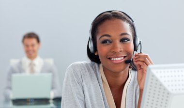 Radiant businesswoman using headset at her desk clipart