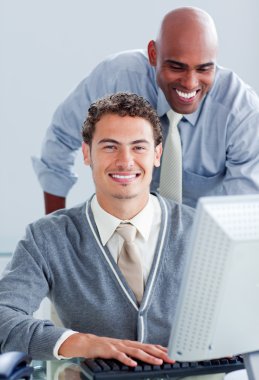 Two attractive businessmen working at a computer clipart