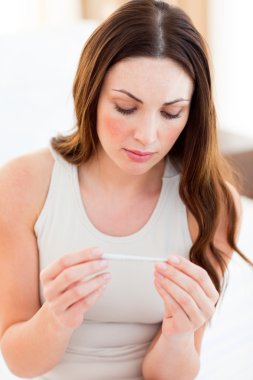 Pensive woman finding out results of a pregancy test clipart