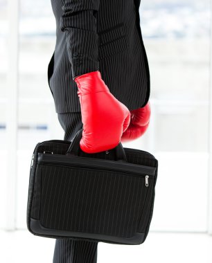 Close-up of a businessman holding a briefcase with boxing gloves clipart