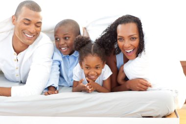 Lively family having fun lying down on bed clipart
