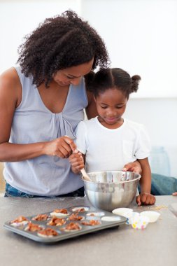 Adorable little girl preparing biscuits with her mother clipart