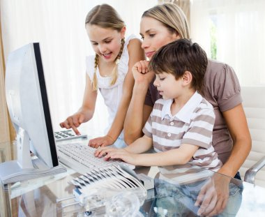Attentive mother teaching her children how to use a computer clipart