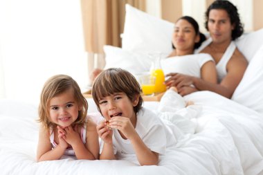 Happy siblings having breakfast with their parents clipart