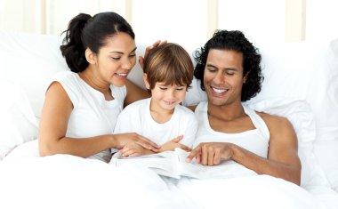 Smiling little boy reading with his parents clipart