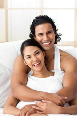 Attractive man hugging his wife lying on the bed clipart