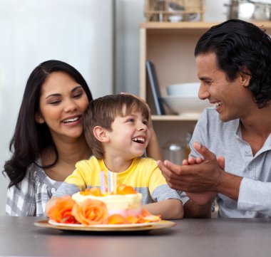 Joyful child celebrating his birthday with his parents clipart