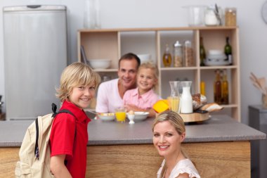 Smiling mother packing the school lunch to his son clipart