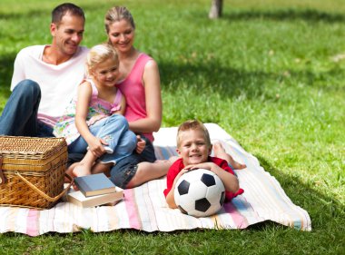 Happy parents and children picnicing in the park clipart