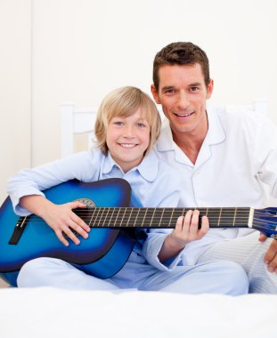 Merry little boy playing guitar with his father clipart