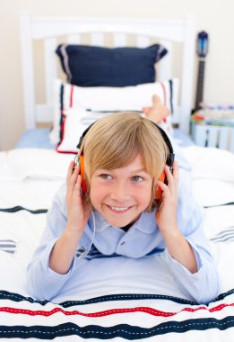 Relaxed boy listening music lying down on bed clipart