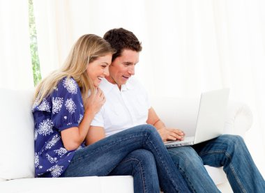 Animated couple using a laptop sitting on sofa clipart