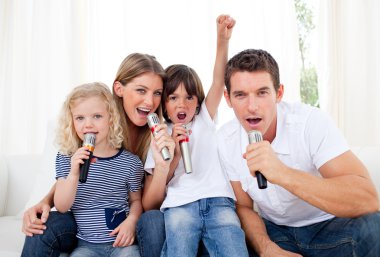 Portrait of a lively family singing through microphone clipart