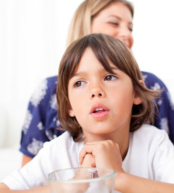 Captivated child watching television with his mother clipart