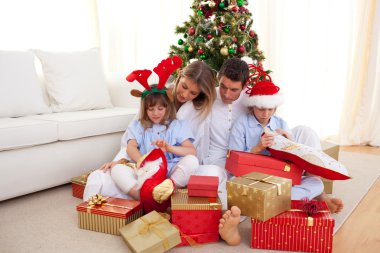 Portrait of a happy family opening Christmas gifts clipart