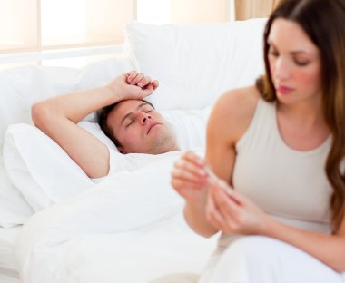Concerned woman taking her sick husband's temperature clipart