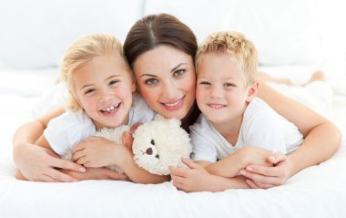 Animated siblings with their mother lying on a bed clipart