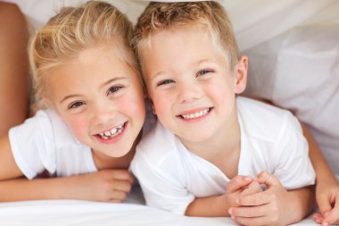 Adorable siblings playing on a bed clipart