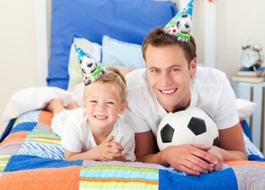 Happy child and his father playing with a soccer ball clipart